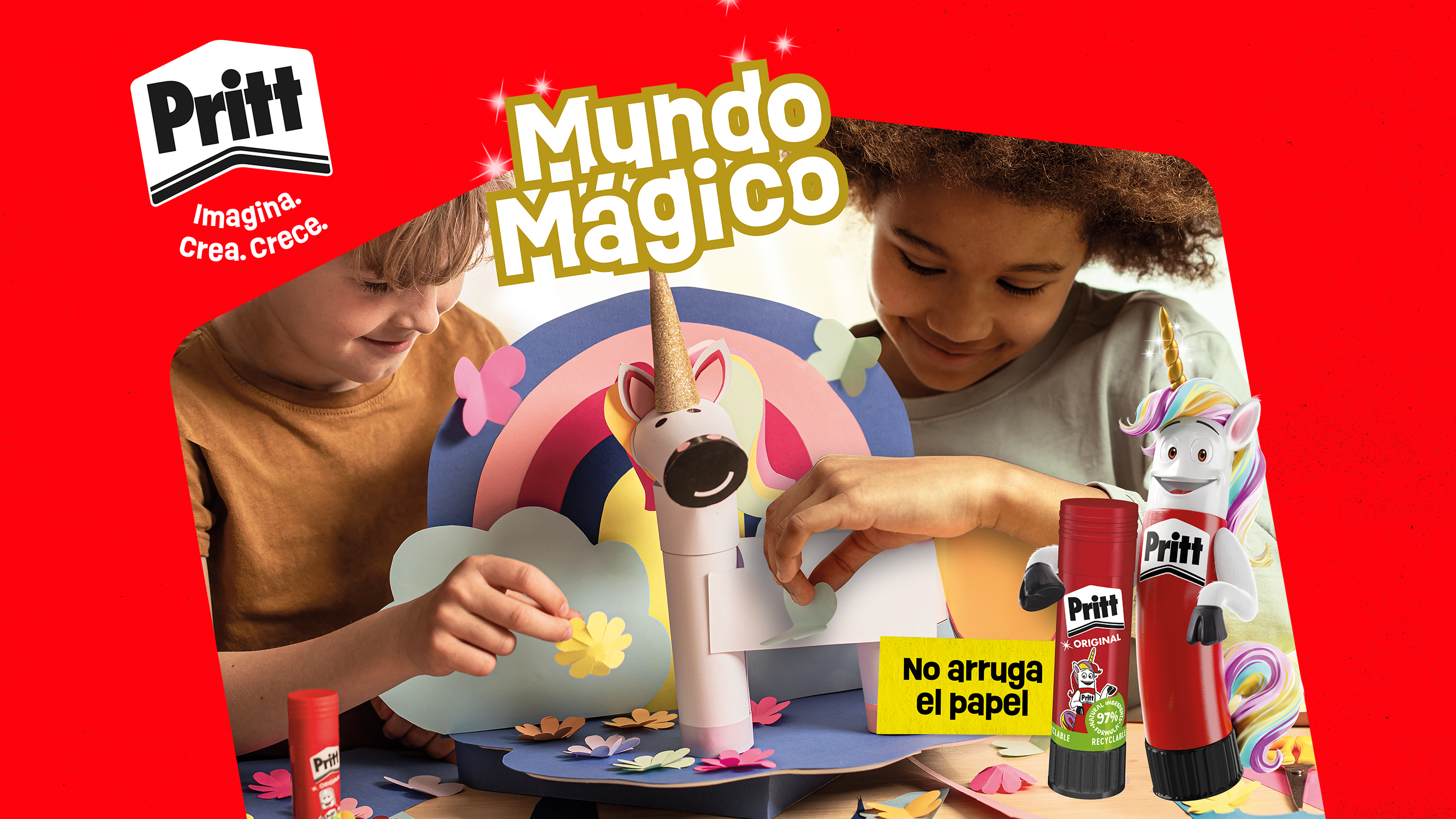 Dos niños realizan una manualidad con figuras de papel de fantasía, entre ellas un unicornio, en una escena de la campaña Mundo Mágico de Pritt. La imagen incluye productos adhesivos de la marca y elementos decorativos de colores.