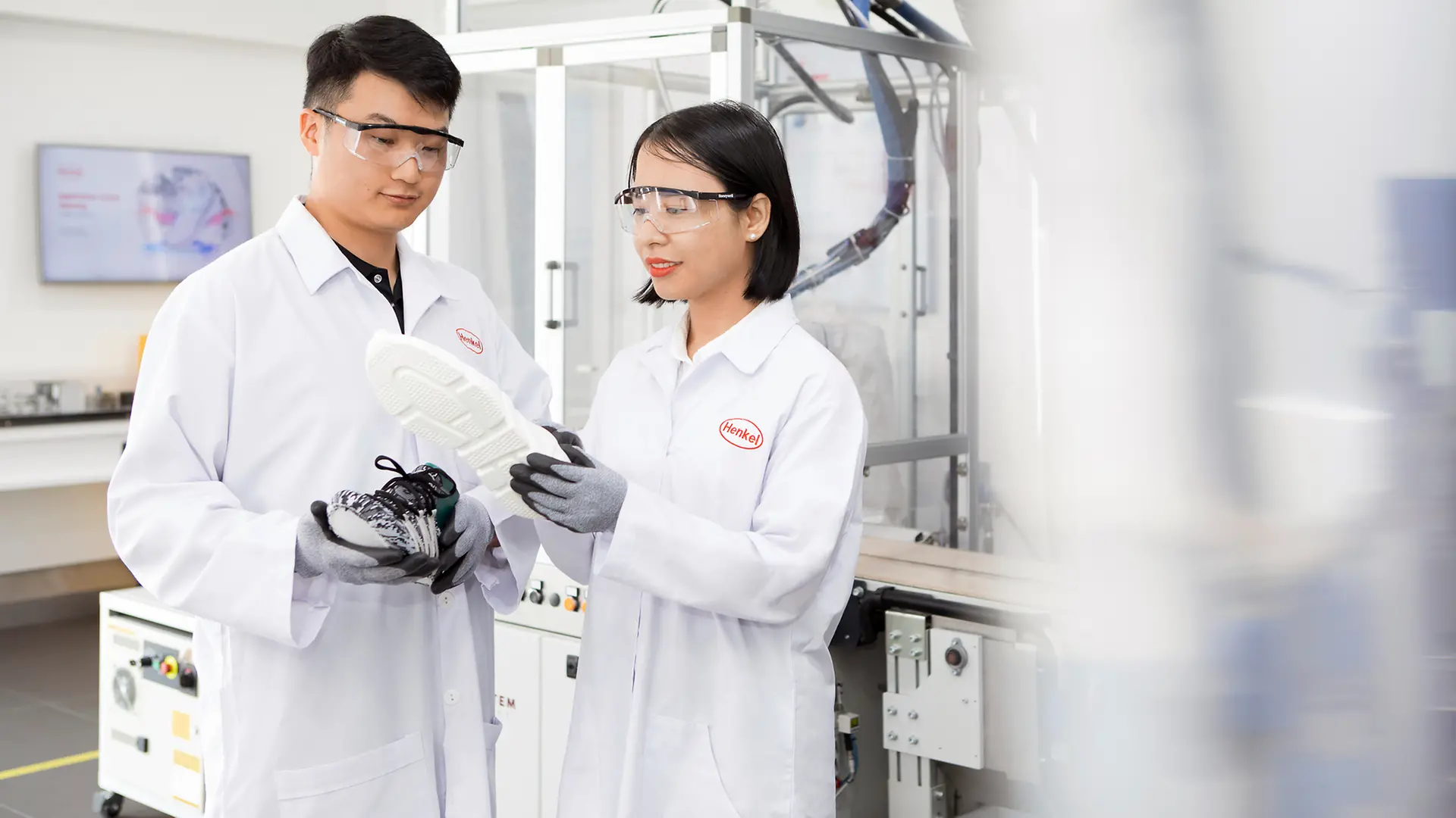 Two Henkel researchers in a laboratory analyze a shoe sole that has been bonded with innovative Henkel adhesives.