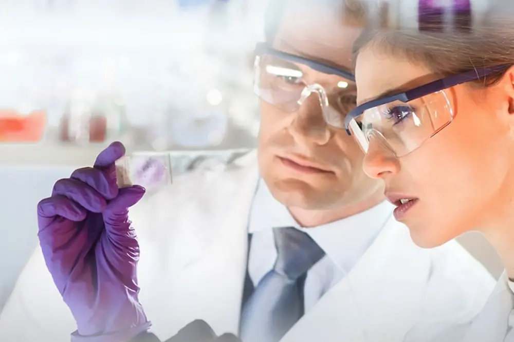 Una mujer y un hombre observando una muestra en un laboratorio