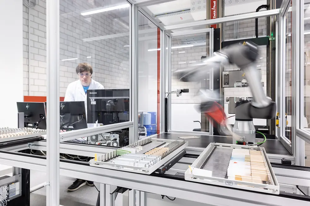 En un laboratorio automatizado, un brazo robótico trabaja con tecnologías adhesivas.