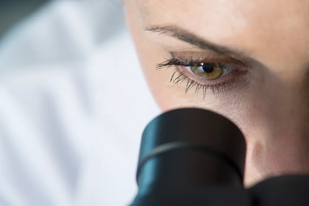 Primer plano de una mujer mirando a través de un microscopio.