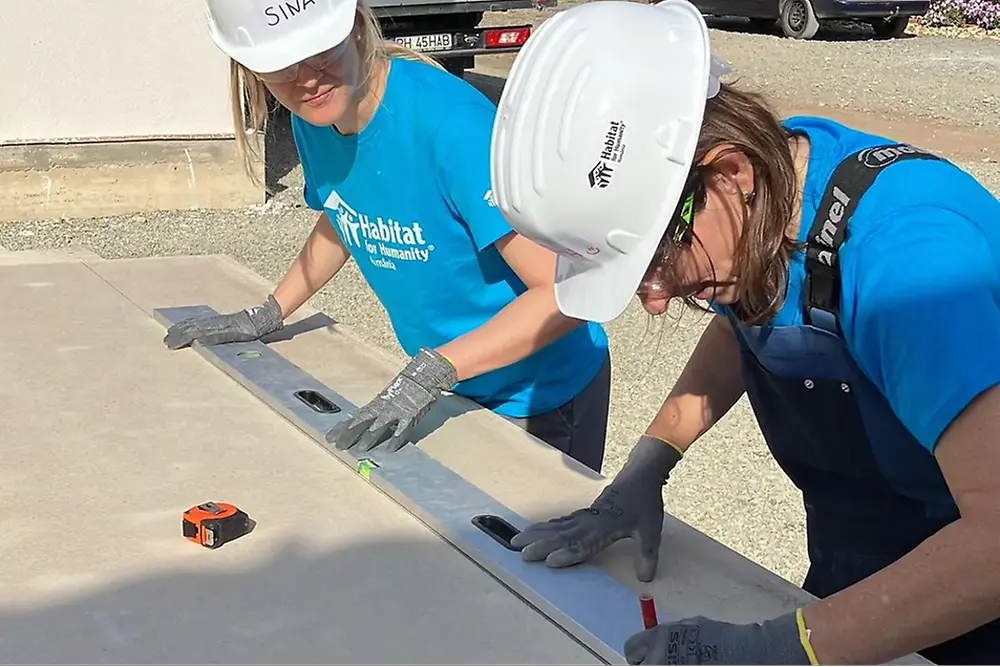 Dos empleadas de Henkel con cascos de seguridad preparando materiales de construcción.