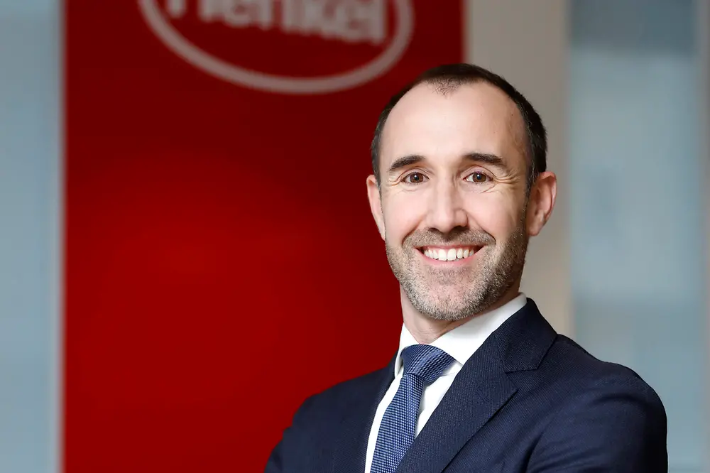 Adrian Orbea posando sonriente frente un cartel de Henkel