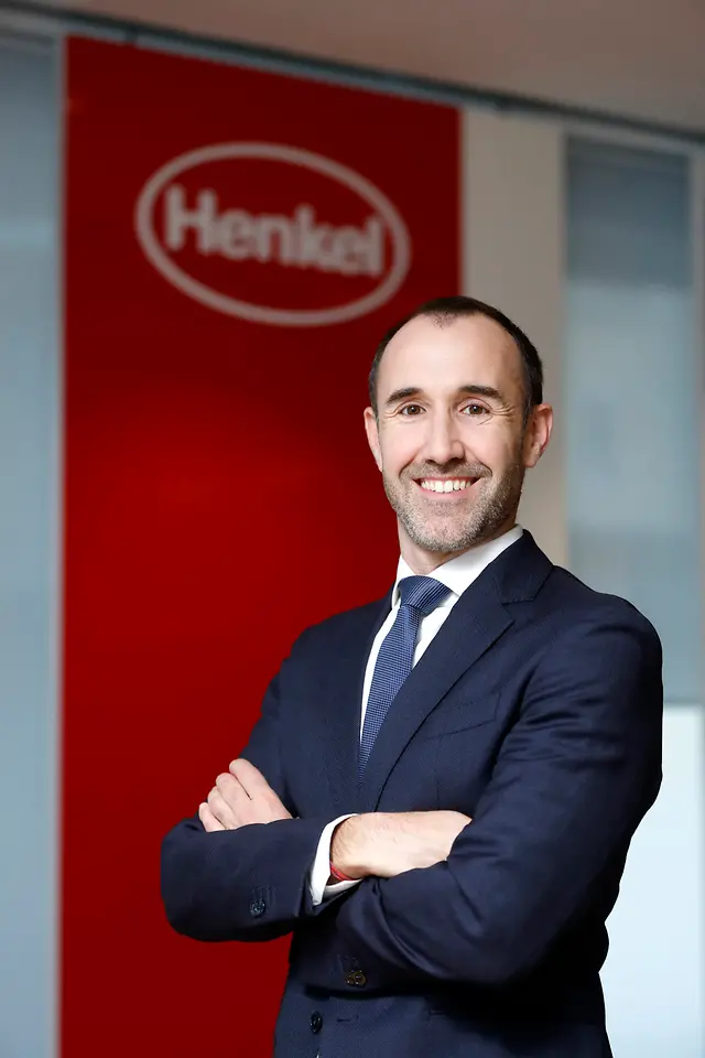 Adrian Orbea posando sonriente frente un cartel de Henkel