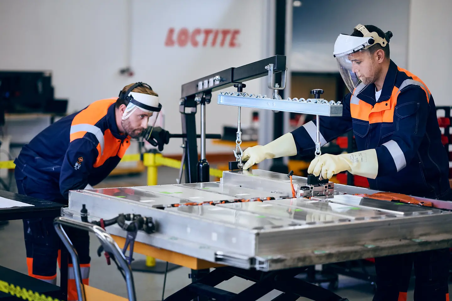 Técnicos trabajando en la reparación de una batería de vehículo eléctrico en un taller, utilizando herramientas y equipos especializados.