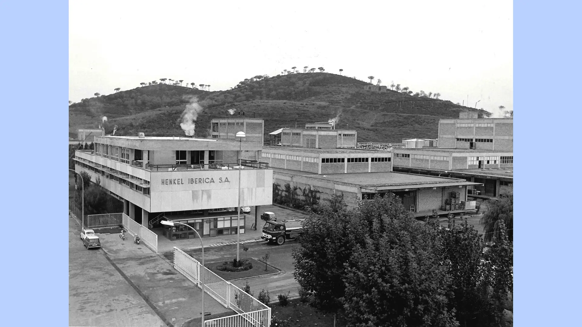 Imagen en blanco y negro del exterior de la planta de Montornès. La foto muestra el complejo industrial con los diferentes edificios rodeados de las montañas de la zona.