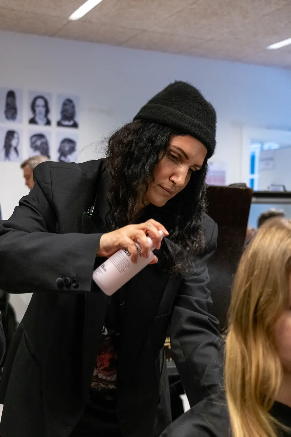 Profesional aplicando un producto de Authentic Beauty Concept al cabello de una modelo en el backstage.