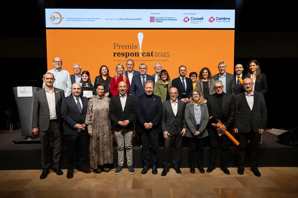 Grupo de personas participantes en la ceremonia de los Premis Respon.cat 2025, posando en el escenario frente a la pantalla oficial del evento.