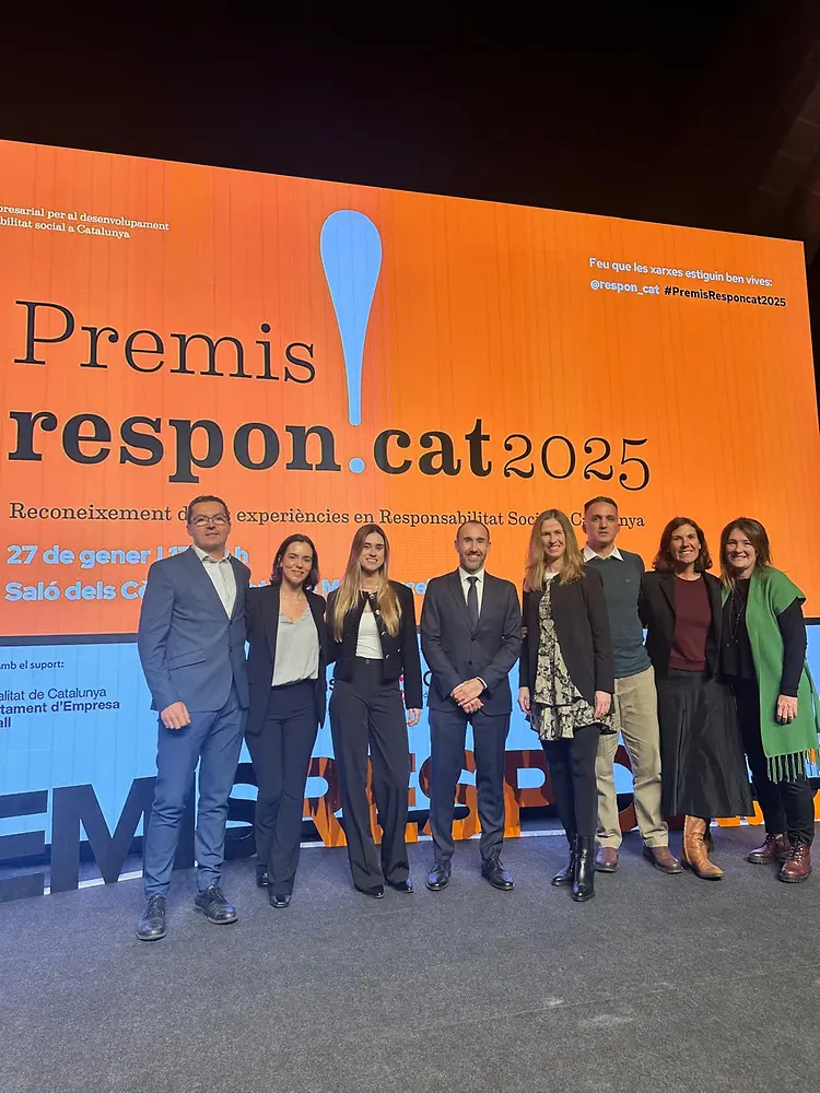Grupo de empleados de Henkel Ibérica posando en el escenario de los Premis Respon.cat 2025, frente a la pantalla oficial del evento.