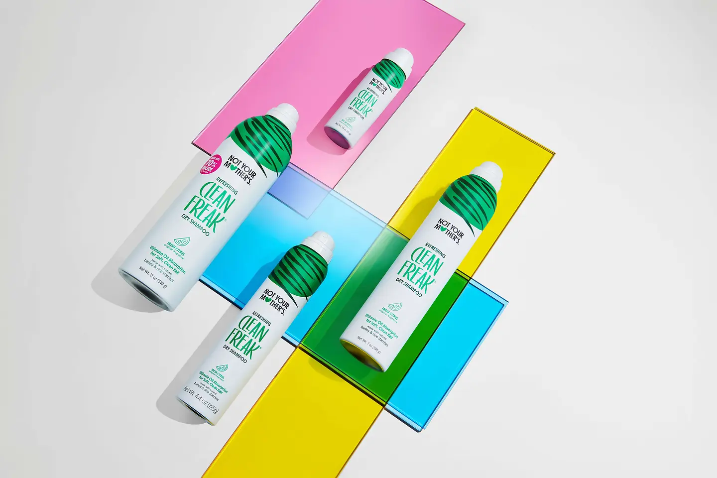 Colección Clean Freak de Not Your Mother’s con champú en seco en distintos formatos sobre un fondo de colores.