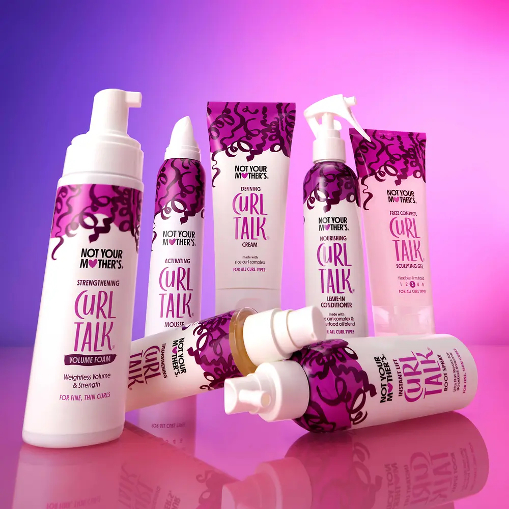 Productos Curl Talk de Not Your Mother’s diseñados para definir y cuidar el cabello rizado, como espuma, crema y acondicionador.