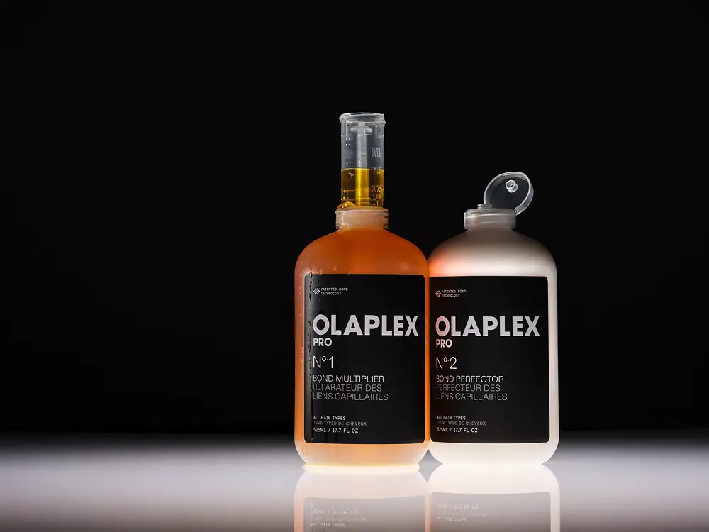 Dos productos profesionales de Olaplex sobre fondo negro.