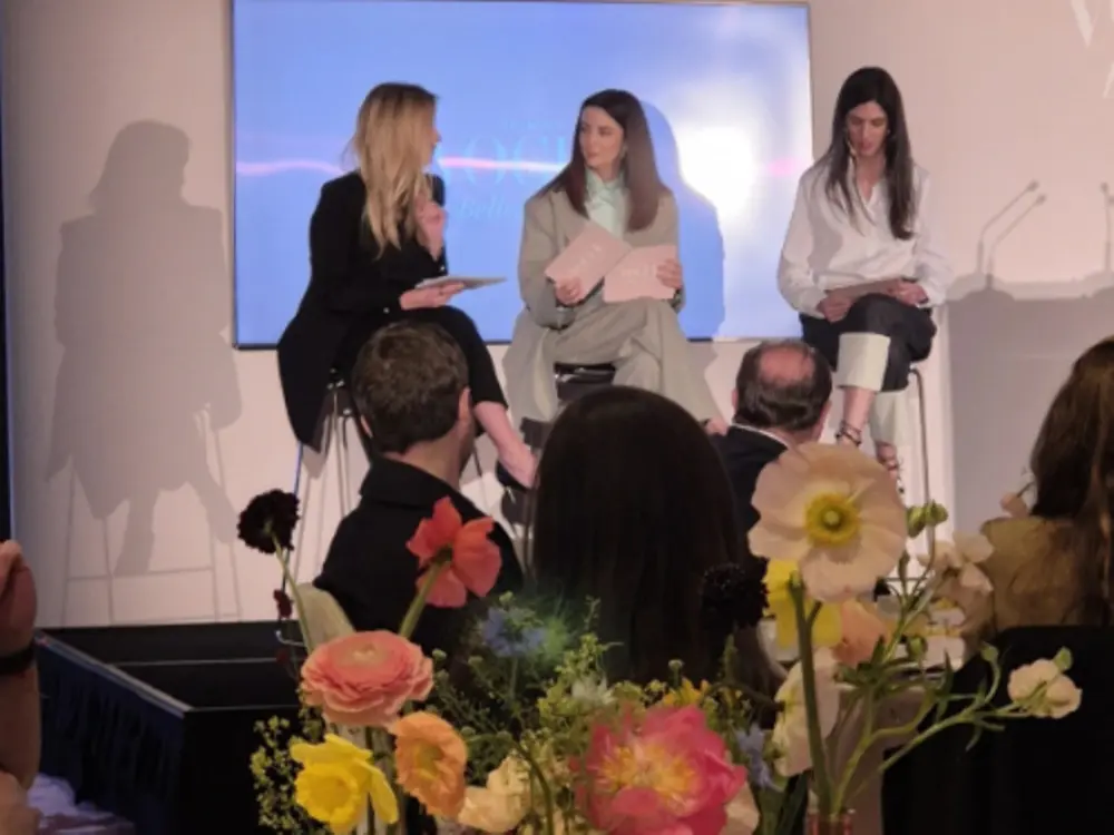 Imagen de un panel de conversación en un evento de los Premios Vogue Belleza, con varias personas sentadas en el escenario frente a una pantalla iluminada, participando en una charla relacionada con el cuidado del cabello.