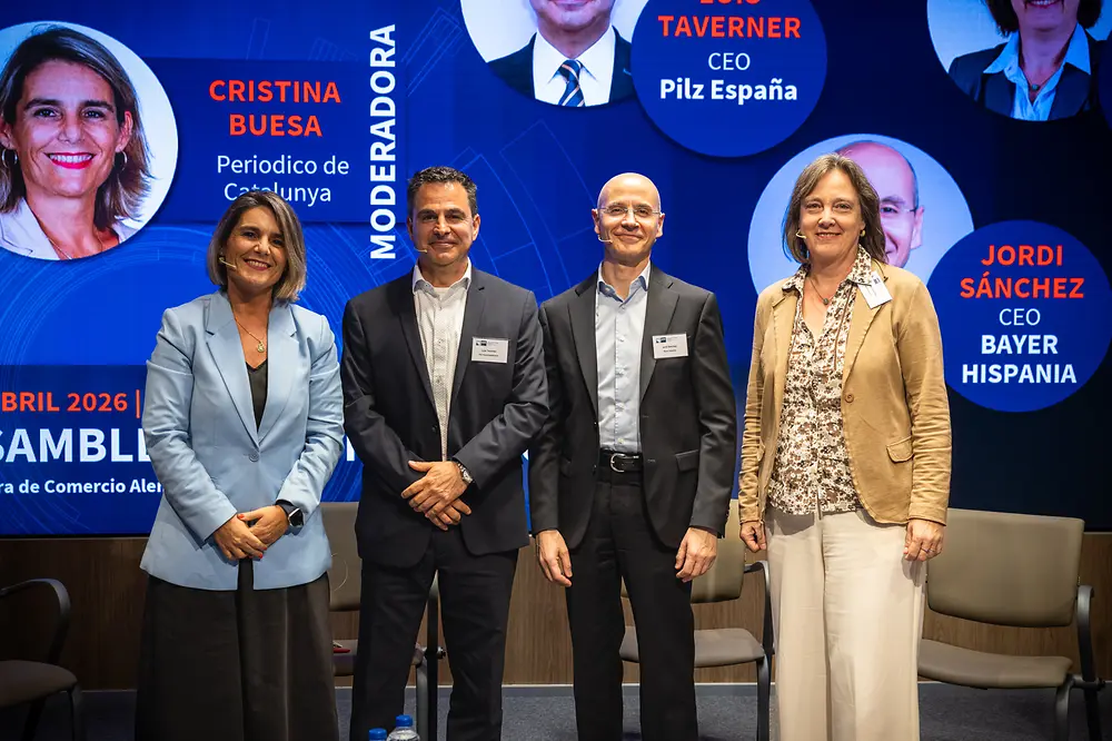 Grupo de directivos, incluida Kirsten Sánchez de Henkel, posando tras una mesa redonda en un evento empresarial en Barcelona con fondo corporativo.