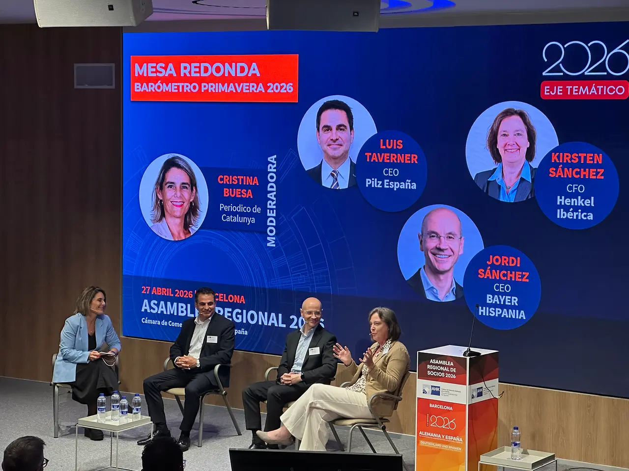 Mesa redonda con directivos de Henkel, Bayer y Pilz en un evento empresarial en Barcelona, con Kirsten Sánchez interviniendo ante el público.