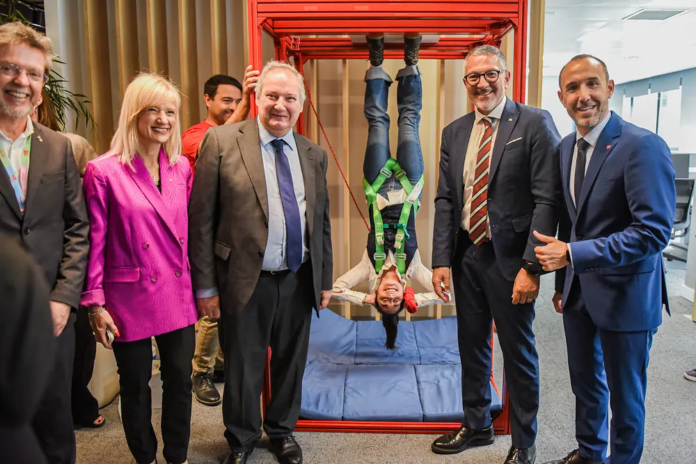 Jordi Hereu y Adrian Orbea posan junto a representantes institucionales y una empleada participando en una instalación interactiva durante la celebración del 150 aniversario de Henkel en Barcelona.