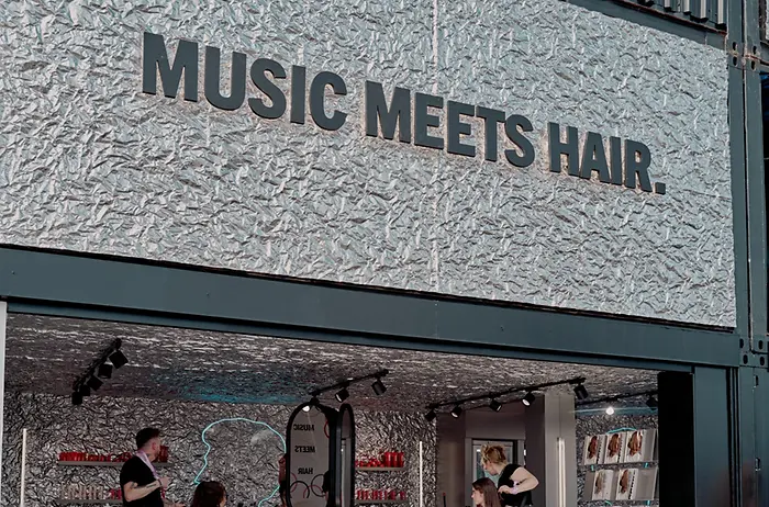 Espacio de styling con el mensaje “MUSIC MEETS HAIR”, donde varios peluqueros trabajan en peinados dentro del salón de Schwarzkopf Professional durante el festival.
