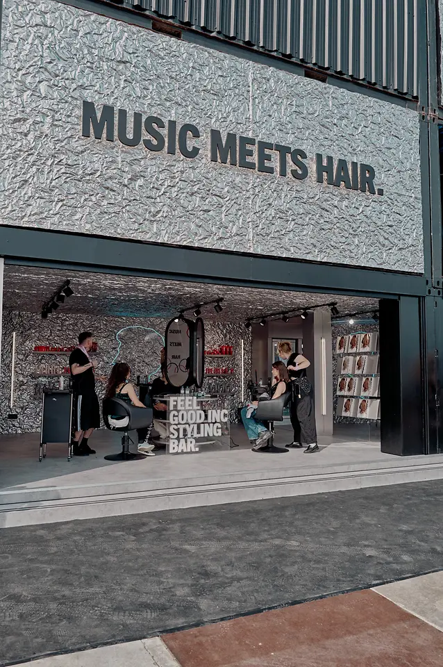 Espacio de styling con el mensaje “MUSIC MEETS HAIR”, donde varios peluqueros trabajan en peinados dentro del salón de Schwarzkopf Professional durante el festival.