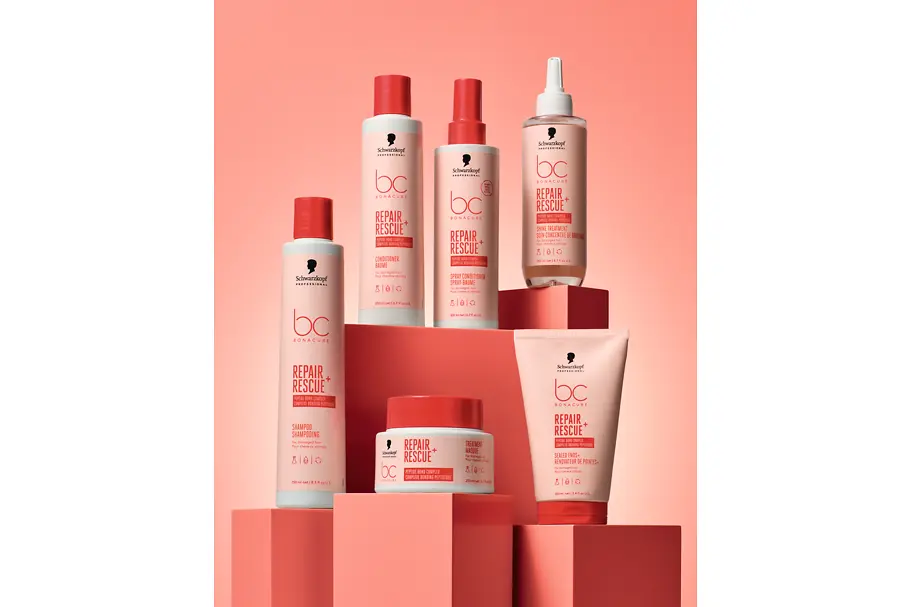 Productos de la gama Bonacure Repair Rescue+ de Schwarzkopf Professional sobre un fondo rosa, incluyendo champú, acondicionador, spray acondicionador y el nuevo Tratamiento Iluminador, diseñados para reparar y fortalecer el cabello dañado