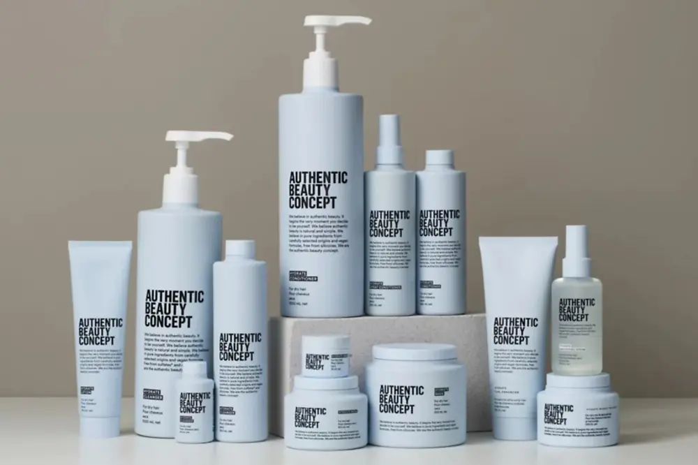 Productos de la gama Hydrate de Authentic Beauty Concept dispuestos sobre una superficie neutra, incluyendo champú, acondicionador, mascarilla, spray acondicionador, loción y tratamientos hidratantes para el cuidado del cabello.