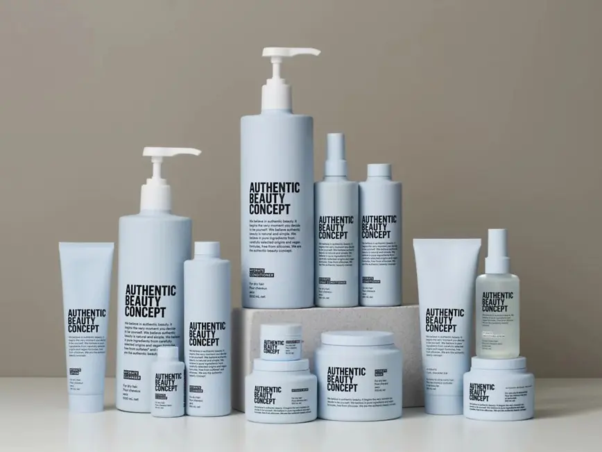 Productos de la gama Hydrate de Authentic Beauty Concept dispuestos sobre una superficie neutra, incluyendo champú, acondicionador, mascarilla, spray acondicionador, loción y tratamientos hidratantes para el cuidado del cabello.