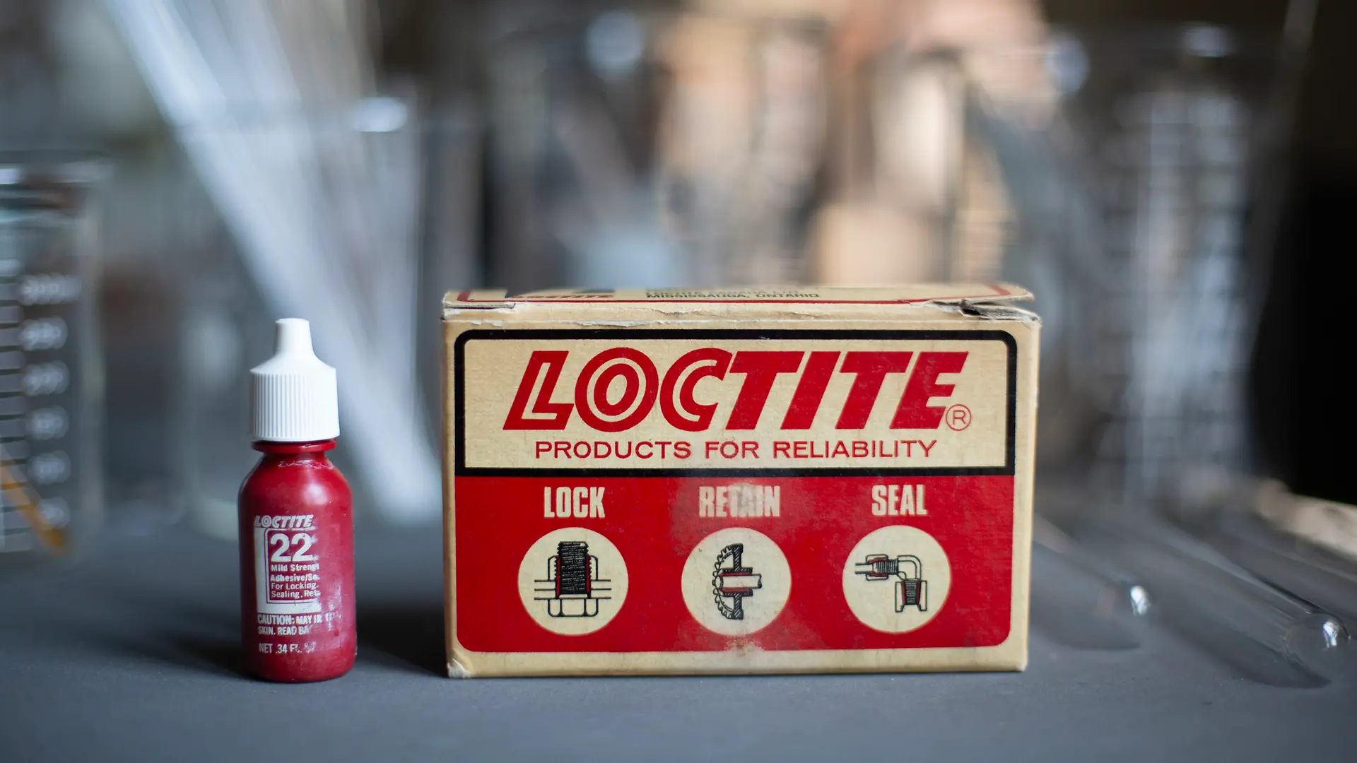 Primeros productos LOCTITE, botella y caja vintage con el lema Lock, Retain, Seal