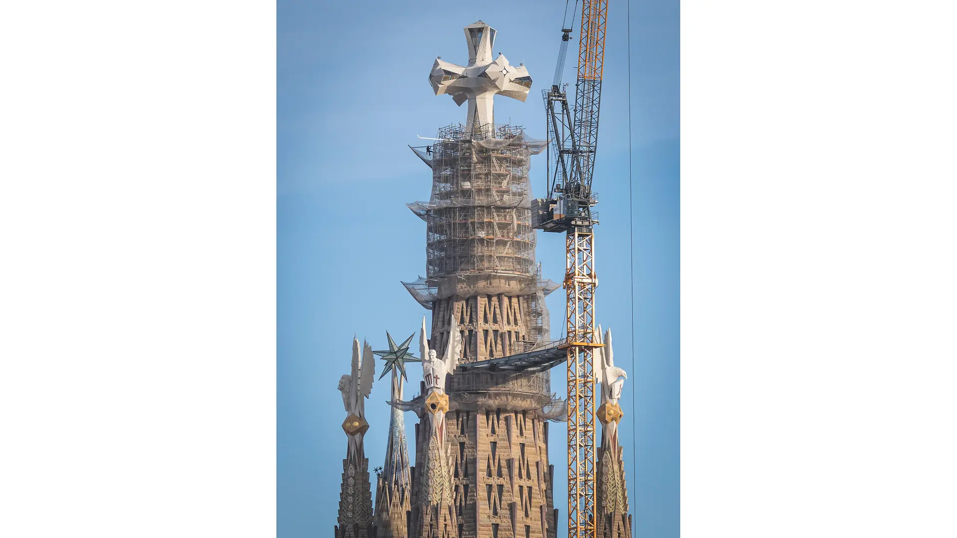 Torres centrales de la Sagrada Familia en construcción, con grúas, al atardecer