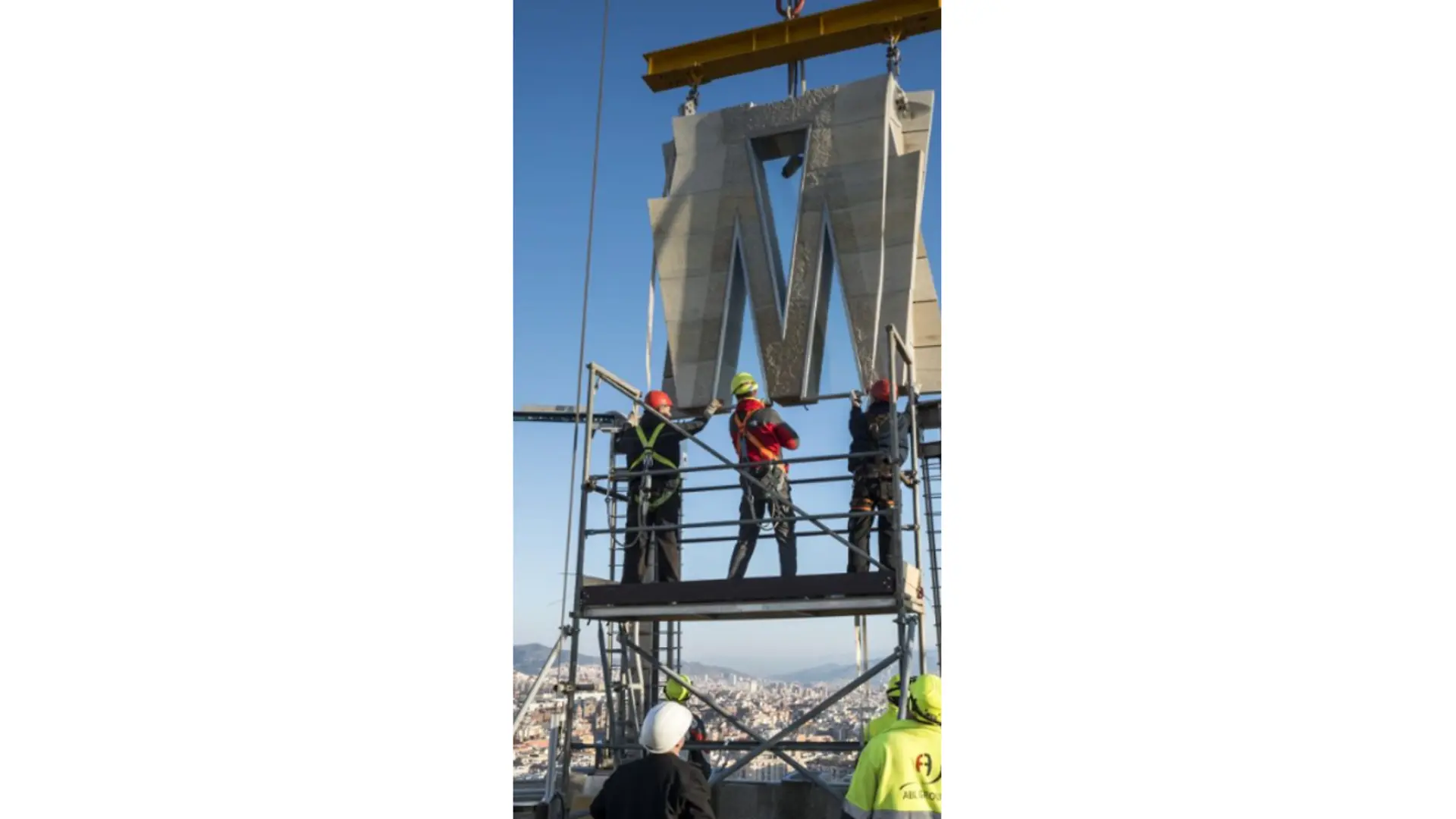 Trabajadores instalando un panel estructural de piedra tesada con grúa en las torres de la Sagrada Familia