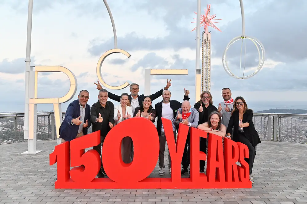 Integrantes del equipo directivo de Henkel Ibérica posan junto a una estructura con el mensaje “150 YEARS” durante el festival conmemorativo del 150 aniversario de Henkel, celebrado en Barcelona, con vistas panorámicas de la ciudad al fondo.