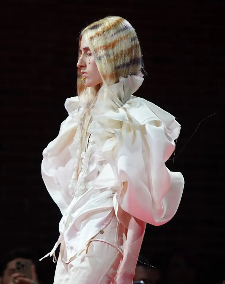 Modelo en pasarela con cabello largo de varios tonos rubios y claros distribuidos en bandas visibles, mostrando un efecto de coloración multidimensional.