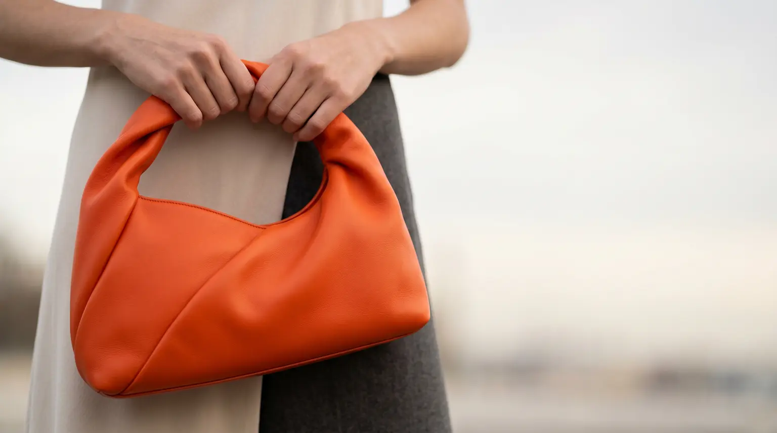 Bolso de cuero naranja sostenido por una persona, ejemplo de aplicación de las soluciones de recubrimientos especiales de Stahl para el sector de la moda y el lujo.