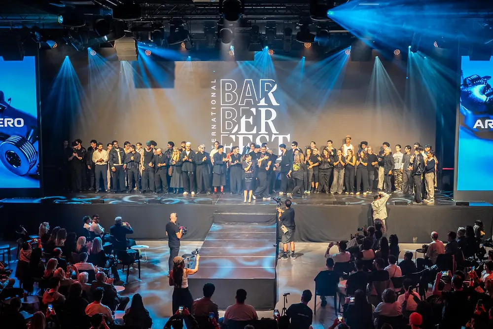Vista general del escenario del International Barber Fest, con decenas de artistas y profesionales de la barbería reunidos frente al público durante la clausura del evento.